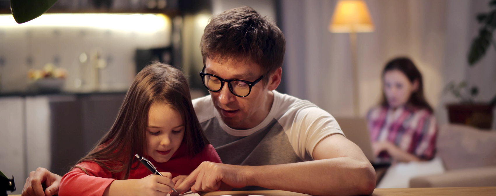 Ein Vater hilft abends seiner kleinen Tochter bei Hausaufgaben